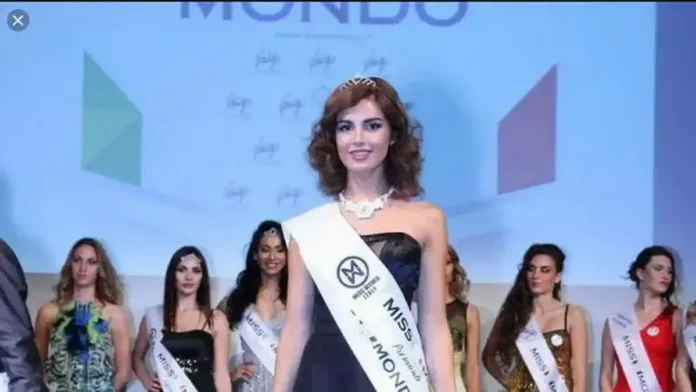 Miss Mondo Piemonte – конкурс красоты в Турине, участницы на сцене во время регионального отбора Широкий кадр сцены конкурса Miss Mondo Piemonte в Турине: участницы в вечерних платьях стоят на подиуме, за спиной светодиодный экран, внизу видна жюри и зрители. Атмосфера элегантного шоу, мягкий сценический свет.