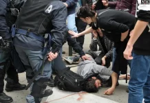 Визит Маттео Сальвини в Турин 28 марта 2015: протесты, столкновения с полицией и слезоточивый газ Протесты в центре Турина: кордон полиции и толпа во время визита Сальвини (2015) сцена в центре Турина, кордоны полиции, толпа на фоне исторических зданий, без лозунгов и читаемых плакатов, дневной свет.