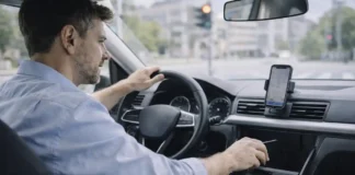 Штрафы и лишение прав в Италии за телефон за рулем: что будет даже на светофоре Штрафы за телефон за рулем в Италии и риск лишения прав на светофоре Водитель в современном автомобиле в Италии убирает телефон в сторону, рядом заметен держатель для навигации, городская улица на фоне, дневной свет