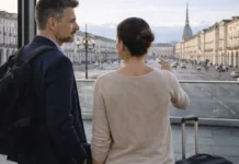 Почему итальянцы возвращаются домой после карьеры за границей? Возвращение в Италию: специалист с чемоданом на фоне Турина Современная городская сцена в Турине, символ возвращения домой после работы за границей, нейтральный деловой настрой