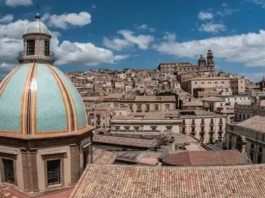 Кальтаджироне перезапуск проекта «дом за 1 евро» к середине 2026 Исторический центр Кальтаджироне (Сицилия), фасады и лестницы с керамикой, на переднем плане папка «Case a 1 euro candidatura»