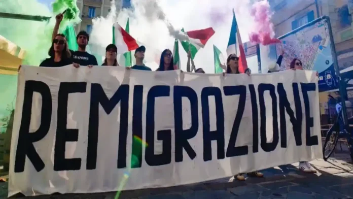 Плакат Remigrazione на площади в Тренто акция Comitato Remigrazione e Riconquista Широкоформатная фотография ночного митинга Comitato Remigrazione e Riconquista в piazza Cantore, Тренто; в кадре баннеры, участники и уличные огни