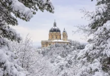 Рождественские снегопады в Италии: рекорды Пьемонта, открытые трассы и риск лавин Базилика ди Суперга после рекордного снегопада в Альпах Пьемонта после рождественского снегопада: заснеженные ели, голубое зимнее небо, чистый свежий снег.