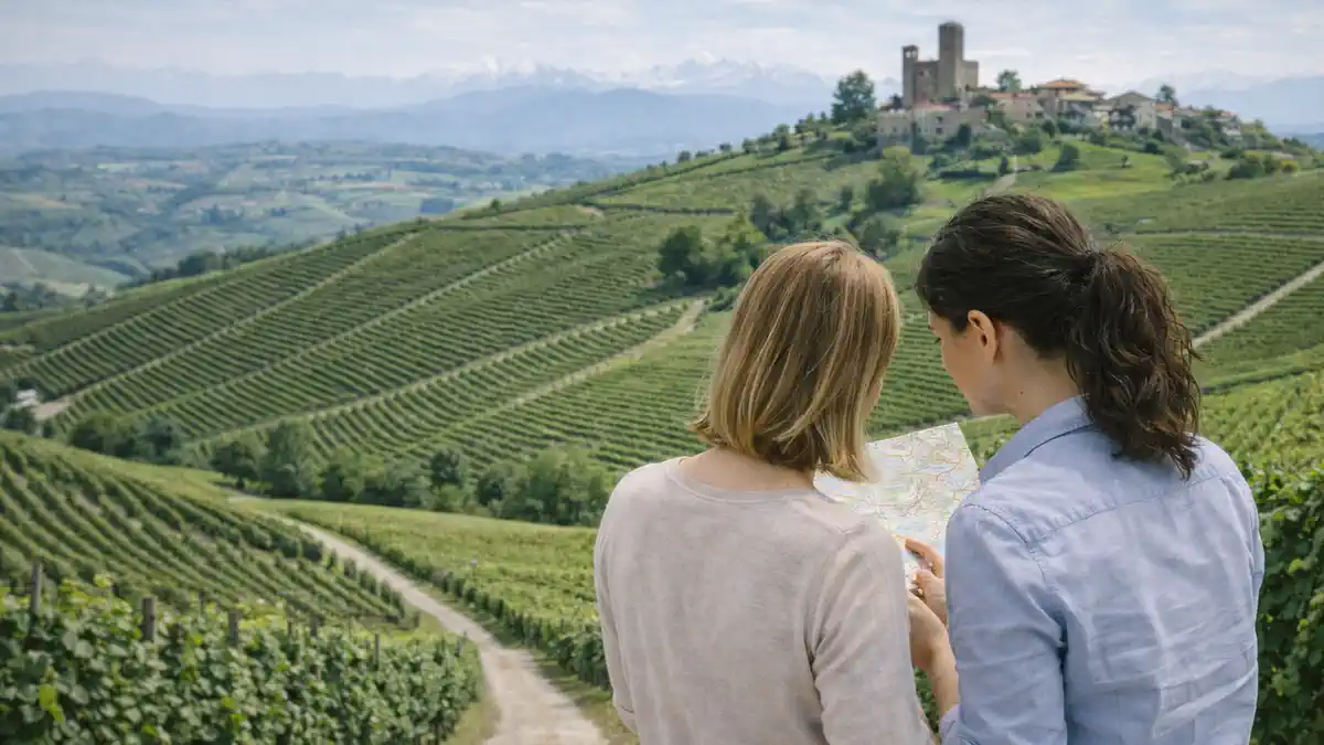 Панорама Пьемонта: холмы с виноградниками, силуэт старинного замка вдали и альпийский фон, атмосфера путешествия по северу Италии.